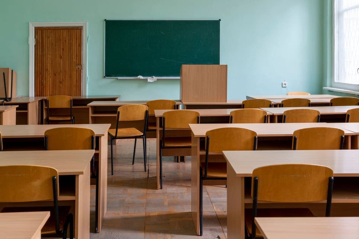 Salle de classe rangée, tableau vert et pupitres en bois