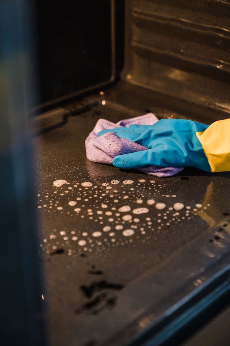 Main gantée dégraissant une surface de cuisson encrassée